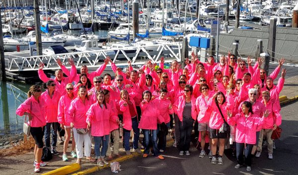 Grand groupe en tenue rose posant au port lors d'un événement d'entreprise