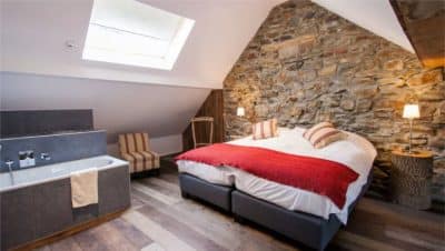 Chambre d'hôtel avec mur en pierre et lit à l'accent rouge