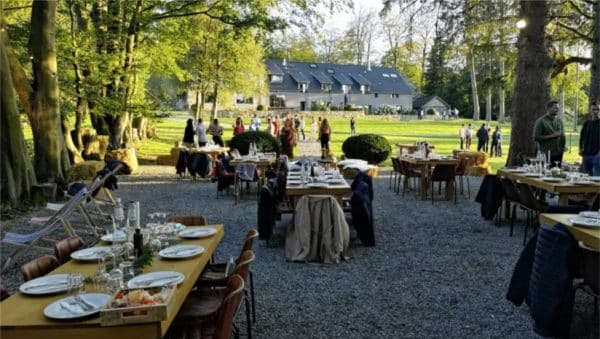 Réception en plein air avec tables dressées dans un jardin devant une villa, événement d'entreprise Xtreme Events