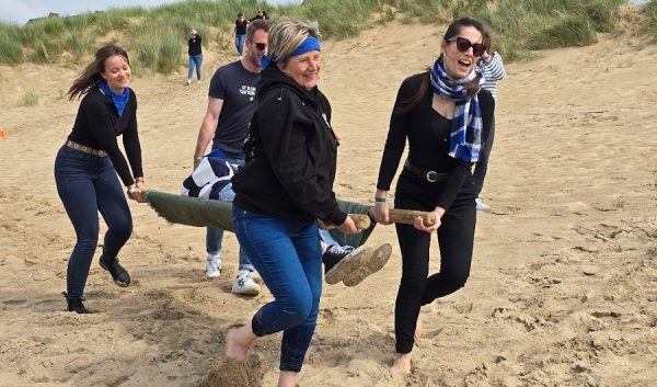 Équipe transportant une planche lors d'un relais sur la plage
