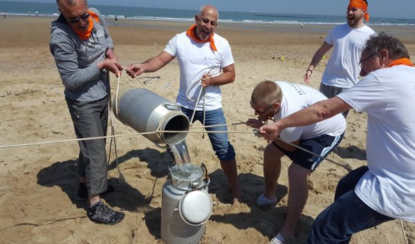 Équipe transvasant de l'eau d'un bidon à l'autre à l'aide de cordes sur la plage