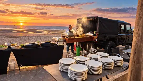 Barbecue préparé par un chef sur la digue, face à la plage au coucher du soleil