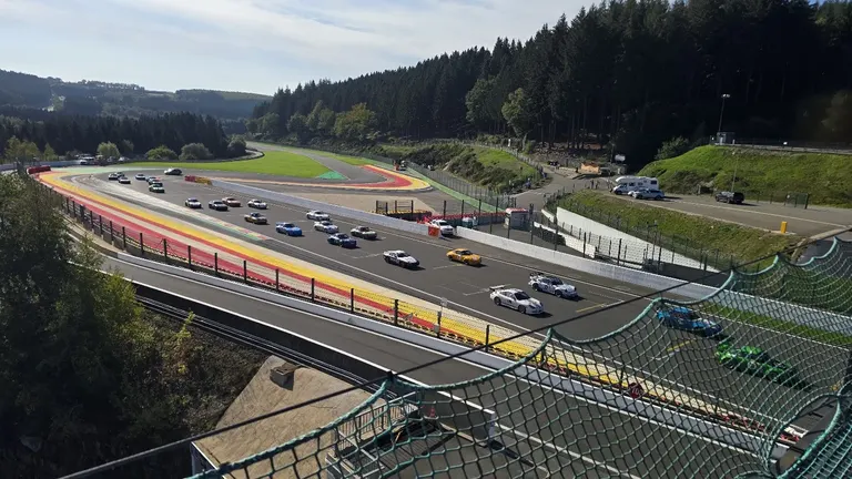 Voitures de course dans la montée de l’Eau Rouge et du Raidillon, vue depuis les hauteurs du circuit