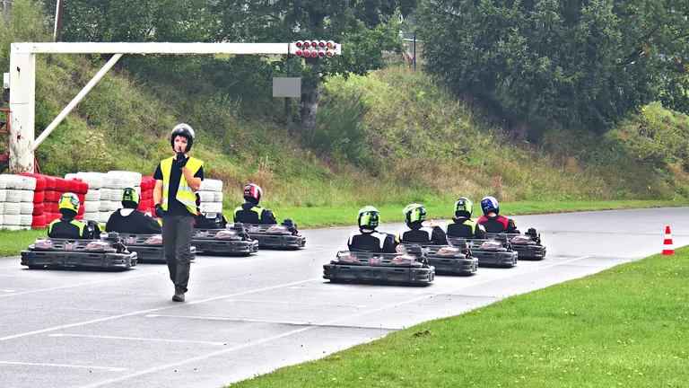 Commissaire de piste devant les karts alignés sous les feux de départ