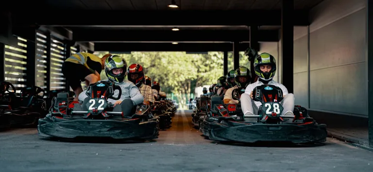 Pilotes casqués alignés dans leurs karts n° 22 et 28 sous l’abri des stands
