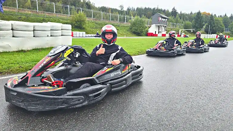 Pilote souriant, pouce levé, dans son kart au bord de la piste