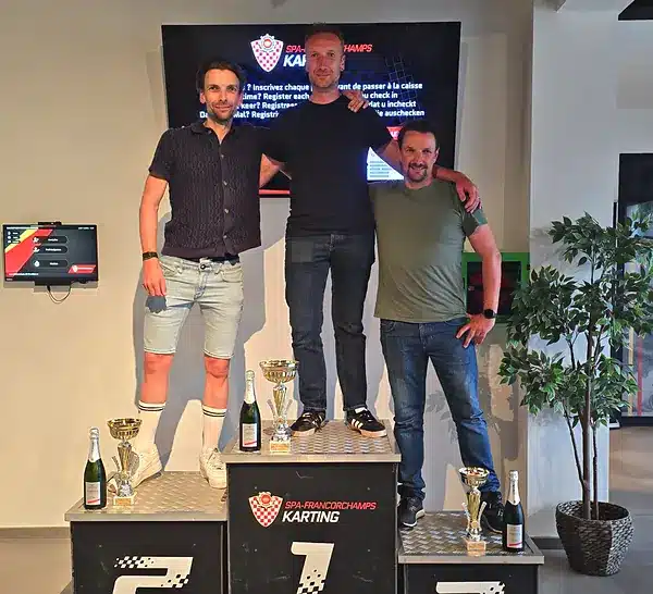 Trois vainqueurs sur le podium du karting de Spa-Francorchamps, avec coupes et champagne