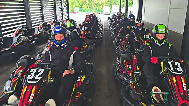 Pilotes équipés dans leurs karts sous l’abri des stands, avant la session