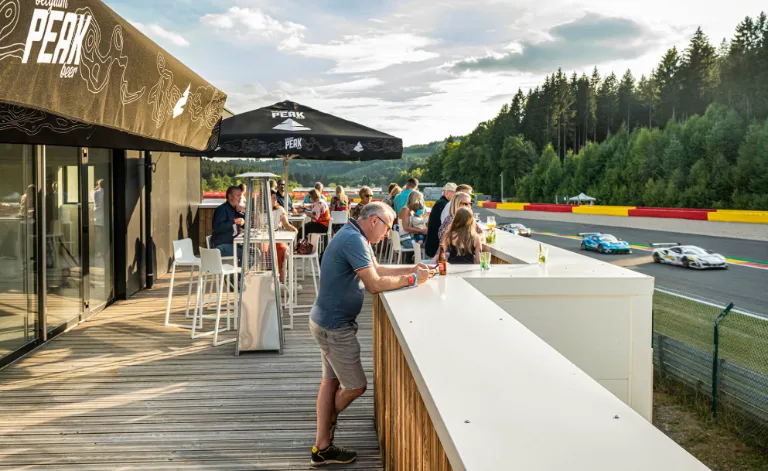 Terrasse rooftop avec bar et tables, vue sur le Circuit de Spa-Francorchamps