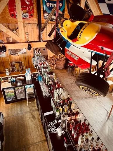 Intérieur du bar L’Arbre qui tue, avec une monoplace suspendue au-dessus du comptoir