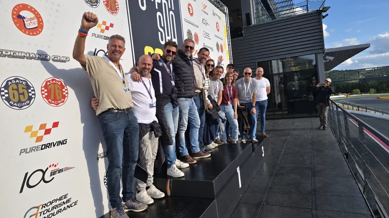 Groupe d’entreprise célébrant sur le podium du Circuit de Spa-Francorchamps, avec la piste en arrière-plan